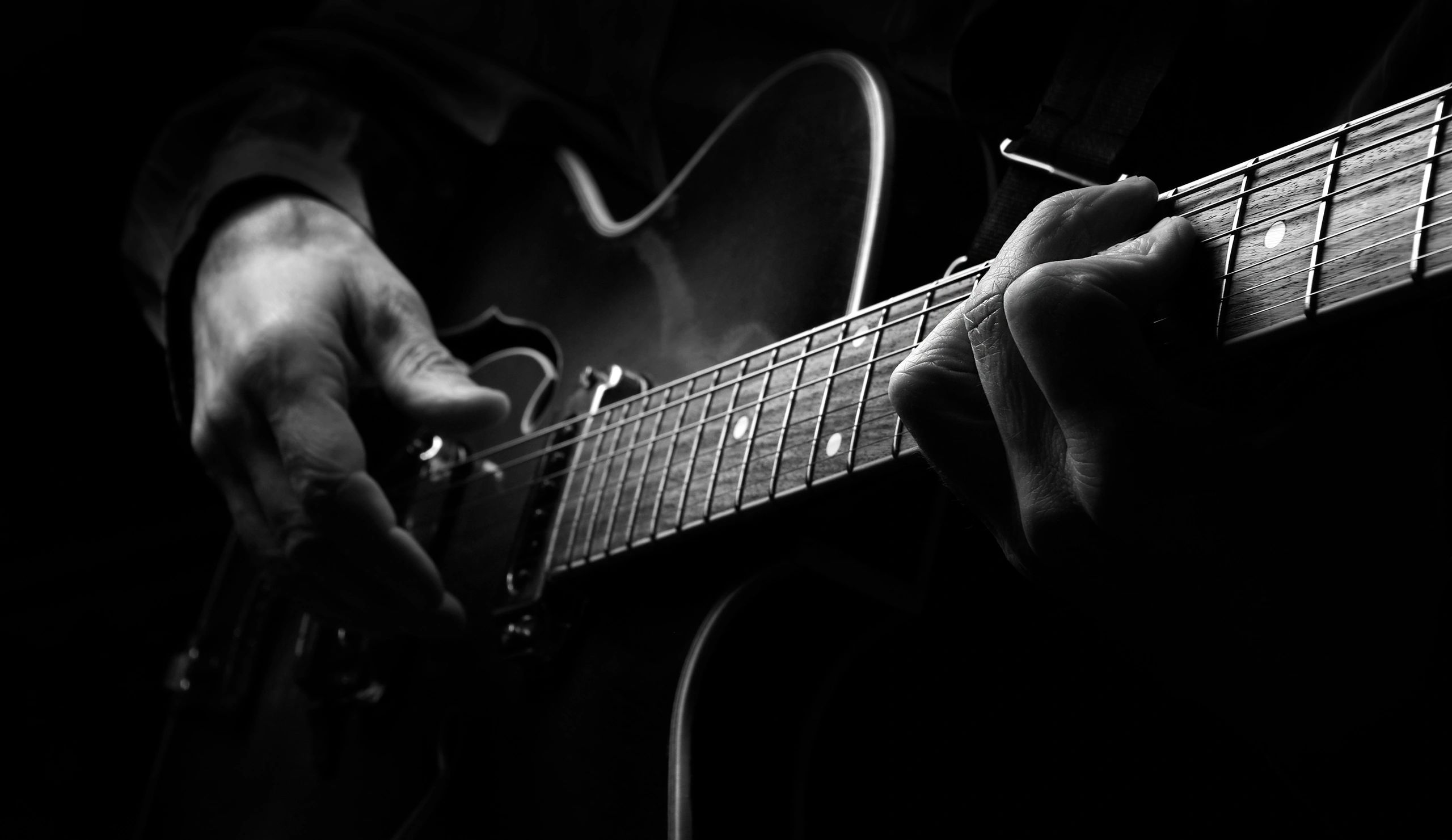 Black and white close-up of acoustic guitar being played
